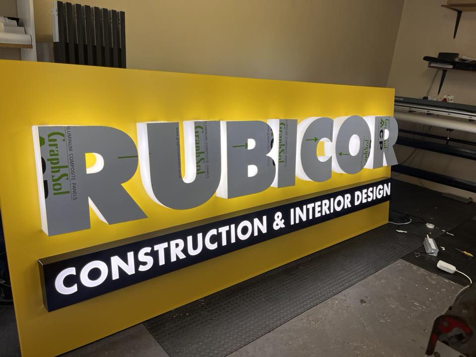 Illuminated light-box lettering staged on a fabrication bench